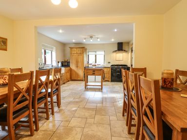 A kitchen with wooden cabinets and two wooden dining tables with chairs at Ty Newydd in Llangadfan