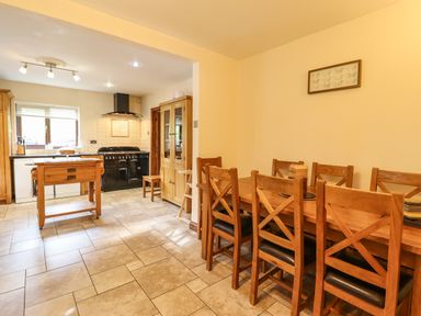 A kitchen and dining area with wooden chairs and table a wooden kitchen island and a black stove at Ty Newydd in Llangadfan