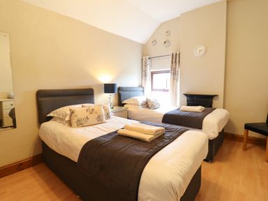 A bedroom with two single beds bedside table lamp and a window at Ty Newydd in Llangadfan