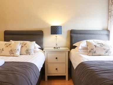 A bedroom with two single beds separated by a white nightstand with a lamp at Ty Newydd in Llangadfan