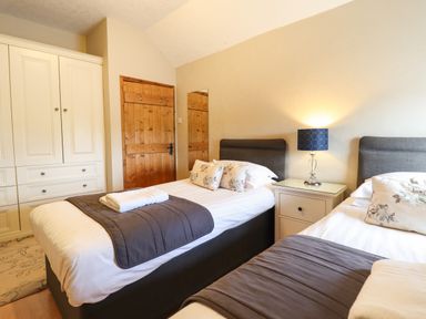 A bedroom with two single beds bedside table lamp and wardrobe at Ty Newydd in Llangadfan
