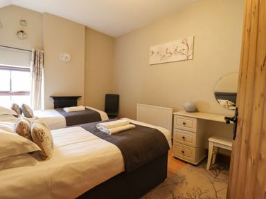 A bedroom with two single beds a desk with a round mirror and a chair at Ty Newydd in Llangadfan