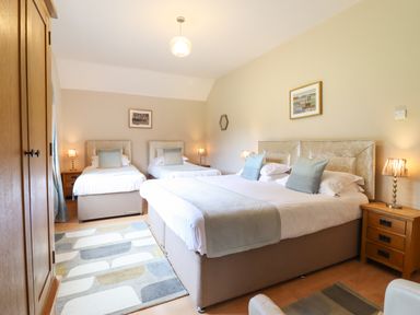 A bedroom with a double bed and two single beds with bedside tables and lamps at Ty Newydd in Llangadfan
