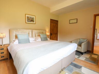 A bedroom with a double bed two bedside tables lamps an armchair and wooden doors at Ty Newydd in Llangadfan