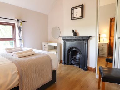 A bedroom with a bed and rolled towels a black fireplace and a white vanity desk at Ty Newydd in Llangadfan