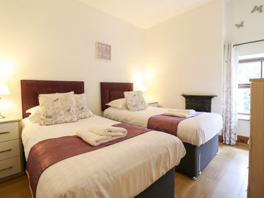 A bedroom with two single beds with folded towels bedside lamps and a window at Ty Newydd in Llangadfan