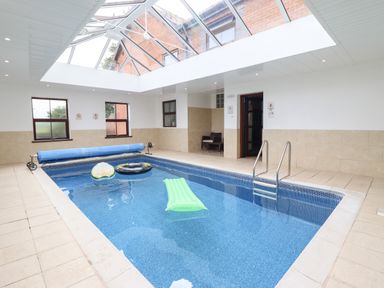 An indoor swimming pool with inflatable floats and a glass ceiling at Ty Newydd in Llangadfan
