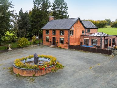 A house with a fountain and flower beds at Ty Newydd in Llangadfan