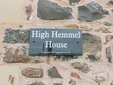 A stone wall with a rectangular sign reading High Hemmel House at High Hemmel House Embleton