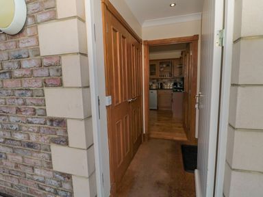 A hallway with wooden doors leading to a kitchen with wooden cabinets at Home Stead Cottage in Embleton