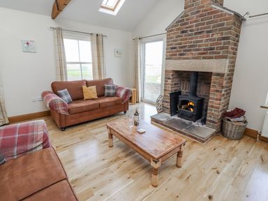 A living room with a fireplace and a sofa at Home Stead Cottage in Embleton