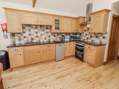 A kitchen with cabinets and appliances at Home Stead Cottage in Embleton