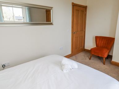 A bedroom with a bed and an orange chair at Home Stead Cottage in Embleton