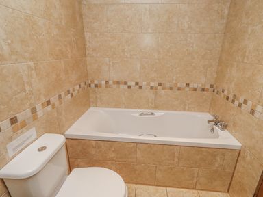 A bathroom with a bathtub and toilet at Home Stead Cottage in Embleton