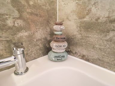 Decorative stones stacked next to a faucet in a bathroom at La Rochelle in Whitby