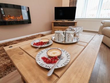 A living room with a coffee table and plates of food at La Rochelle in Whitby