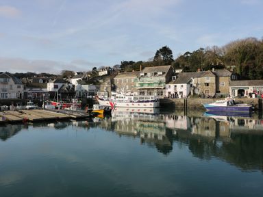 A harbor with boats docked near stone buildings and trees in St Merryn near Padstow