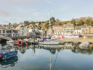 A marina with boats docked near buildings and hills at Tiggy Winkle in St Merryn near Padstow