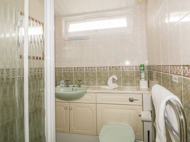 A bathroom with a shower cubicle sink toilet towel rack and tiled walls at Tiggy Winkle in St Merryn near Padstow