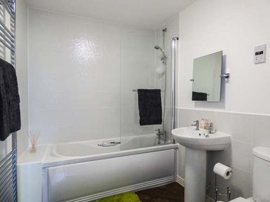 A bathroom with a bathtub a shower a sink with toiletries a mirror and a toilet at Tehidy in Charlestown