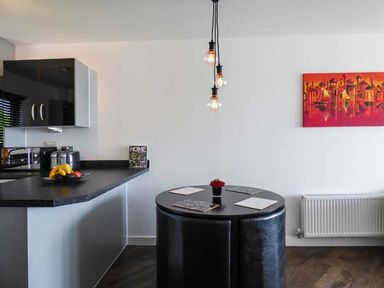 A kitchen with a black countertop and a round black dining table with black chairs at Tehidy in Charlestown