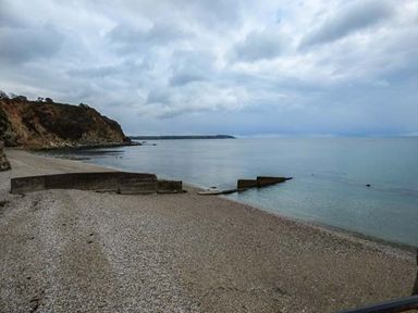 A pebble beach with a concrete sea wall and cliffs at Tehidy in Charlestown