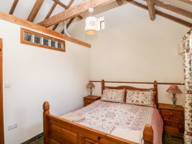 A bedroom with a wooden bed and two bedside tables with lamps at The Long Barn in Hasguard near Little Haven