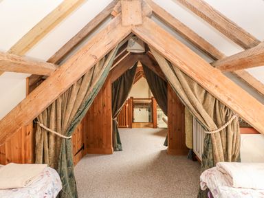 A carpeted attic hallway with wooden beams and curtains tied back at The Long Barn in Hasguard near Little Haven