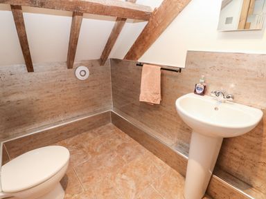 A bathroom with a toilet sink hand soap and towel on a rack at The Long Barn in Hasguard near Little Haven