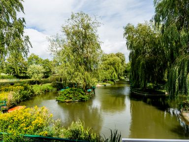 A narrow river with small tree-covered islands and greenery along the banks at Grafton Mill in Grafton Flyford near Pershore