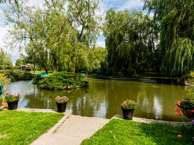 A pond surrounded by trees with flower pots on the edge of a stone path at Grafton Mill in Grafton Flyford near Pershore
