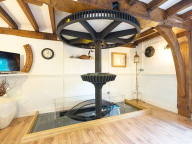 A room with wooden beams and a large black gear mechanism displayed in the center at Grafton Mill in Grafton Flyford near Pershore