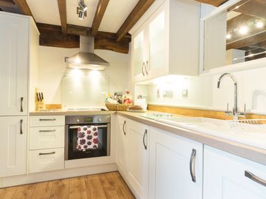 A kitchen with white cabinets wooden countertops a stainless steel oven and stove a basket of groceries a sink and a faucet at Grafton Mill in Grafton Flyford near Pershore