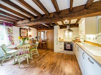A kitchen and dining area with wooden beams and a round table with chairs at Grafton Mill in Grafton Flyford near Pershore