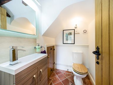 A bathroom with a toilet and a wooden cabinet under a sink at Grafton Mill in Grafton Flyford near Pershore