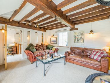 A living room with wooden beams two sofas a glass coffee table and wall art at Grafton Mill in Grafton Flyford near Pershore
