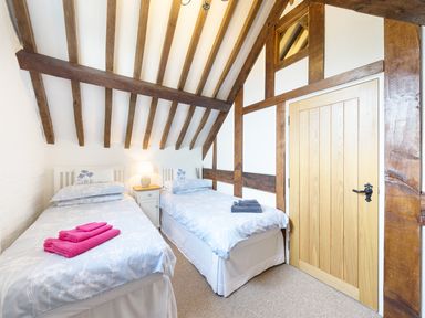 A bedroom with two single beds a nightstand with a lamp and wooden beams on the ceiling at Grafton Mill in Grafton Flyford near Pershore