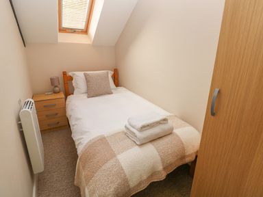 A small bedroom with a single bed bedside table and a window at Kingfisher in Blaenwaun