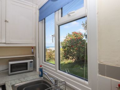 A kitchen with a window and a microwave at Highdown in Bigbury on Sea near Modbury
