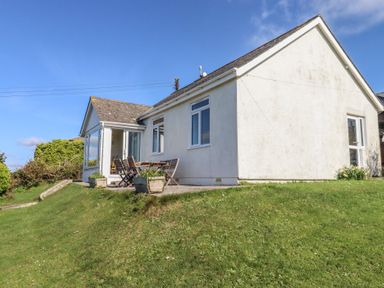 A house with windows and a seating area at Highdown in Bigbury on Sea near Modbury