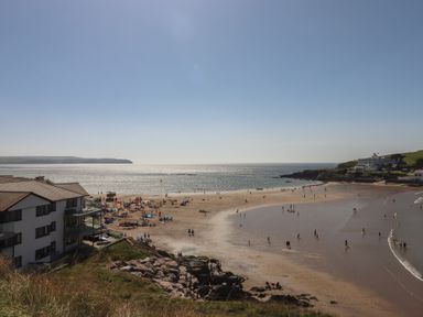 A beach with people and buildings near the ocean at Highdown in Bigbury on Sea near Modbury
