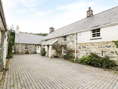 An outdoor stone courtyard with stone buildings and windows at Hen Gelligemlyn - The Annexe in Ganllwyd