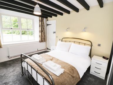 A bedroom with a bed with white linens and folded towels bedside tables and a window at Hen Gelligemlyn - The Annexe in Ganllwyd
