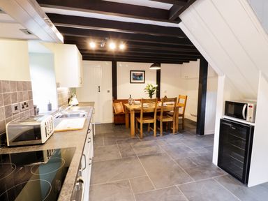 A kitchen with a dining table and chairs and a microwave and toaster at Hen Gelligemlyn - The Annexe in Ganllwyd