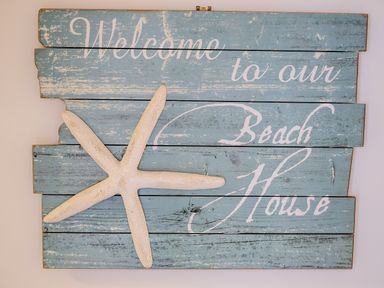 A blue wooden wall sign with white text and a starfish decoration at Stones Throw in Charlestown