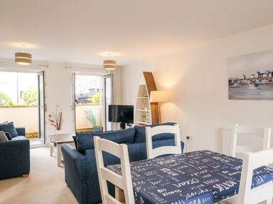 A living room with blue sofas dining table with navy tablecloth and white chairs at Stone's Throw in Charlestown