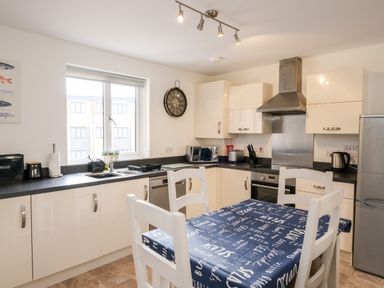 A kitchen with white cabinets a table with a blue tablecloth and four white chairs at Stones Throw in Charlestown