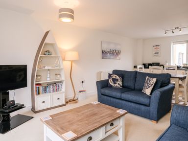 A living room with blue sofas wooden coffee table boat-shaped bookshelf and dining table at Stones Throw in Charlestown