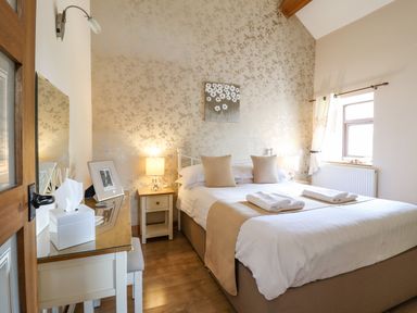 A bedroom with a double bed two bedside tables lamps a dressing table and a window at Bwthyn Ty Newydd in Llangadfan