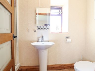 A bathroom with a pedestal sink mirror window and toilet at Bwthyn Ty Newydd in Llangadfan